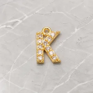 Close-up of golden letter K pendant with micro-paved cubic zirconia and hanging loop