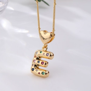Macro detail of gold letter E pendant with multi-colored zircon stones and heart bail