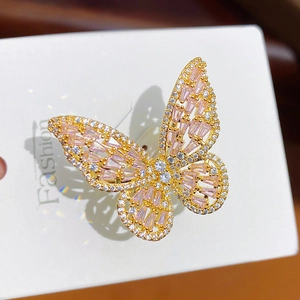 Gedetailleerde close-up van een gouden vlinderring met roze en witte zirkonia steentjes