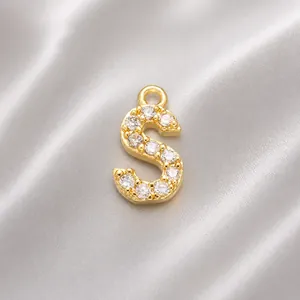 Detail of S-shaped pendant with gold plating and sparkling zircon stones for jewelry making