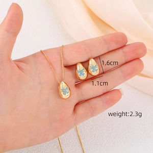 Detailed view of water drop jewelry set with butterfly pattern held in hand for scale