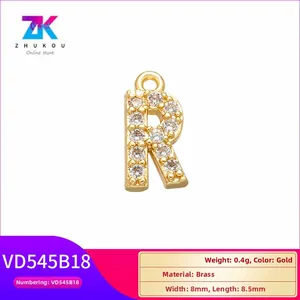 Macro view of a gold brass 'R' letter pendant with white cubic zirconia micro-inlay