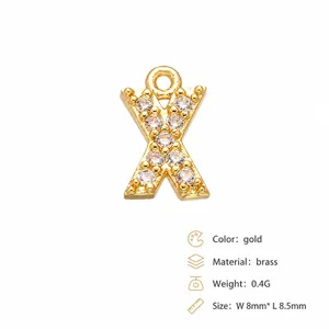 Macro detail of gold plated letter X pendant with sparkling zircon and brass finish