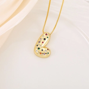 Gros plan du collier pendentif doré orné de zircons colorés sur plateau en satin blanc