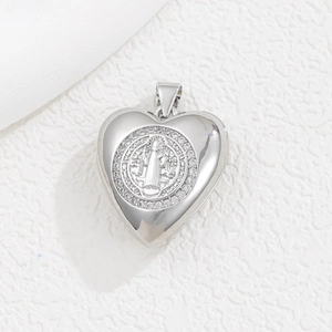 Makroaufnahme des silbernen Herzanhängers mit Benediktus-Medaille und funkelnden Zirkonia
