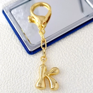 Macro view of 18K gold letter K bubble pendant with spring clasp and polished finish