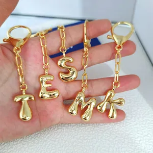 Detail view of 3D puffy gold letter charms T E S M K with polished metallic finish