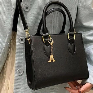 Elegante borsa in pelle nera con ciondolo di lusso in metallo dorato con lettera A