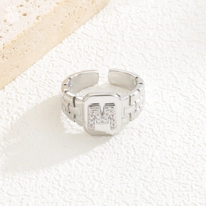 Makroaufnahme eines silbernen Rings mit Zirkonia-Buchstaben M auf einem Gliederkettenband