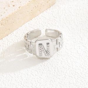 Detailansicht eines silbernen geometrischen Rings mit Zirkonia-Buchstabe N auf Platte