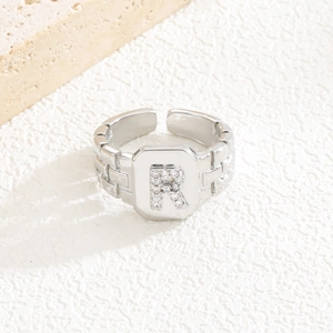 Detailaufnahme des silbernen Rings mit Zirkon-Buchstabe R und strukturierter Schiene
