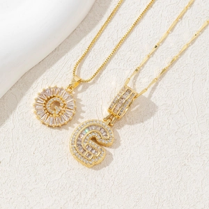 Detail shot of gold letter G necklaces with baguette and round cubic zirconia stones