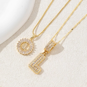 Detailed macro of two gold-plated necklaces with iced-out letter L and zircon pavé settings