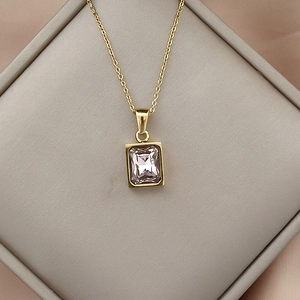 Detail of pink rectangular zircon pendant in gold plating on elegant pink silk cloth