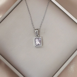 Macro shot of silver necklace with rectangular lavender zircon pendant on silk