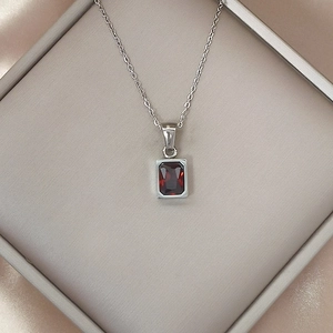Detailed view of silver necklace featuring a rectangle red zircon pendant in a luxury box
