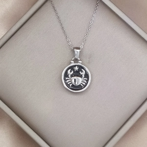 Vintage Cancer zodiac sign necklace with silver relief crab pendant on black background