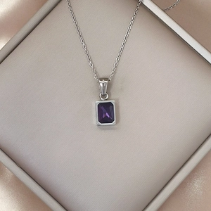 Detail of luxury square purple zircon pendant necklace on champagne silk in a gift box