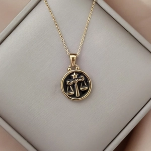 Close-up of Libra zodiac pendant with black enamel inlay in a luxury jewelry box