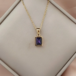 Macro detail of 18K gold stainless steel necklace with square purple zircon pendant