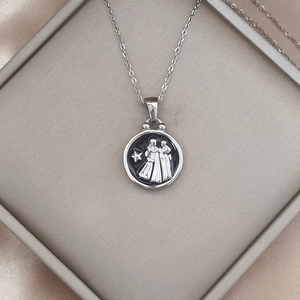 Detailed close-up of a silver zodiac pendant in a luxury jewelry box with silk lining