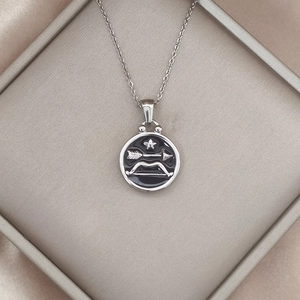 Detailed view of silver Sagittarius zodiac pendant with black enamel in a luxury box