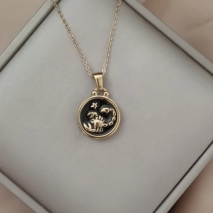 Detailed close-up of a gold Scorpio coin pendant with black enamel on a silk fabric