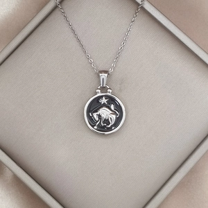 Detailed macro view of Taurus zodiac pendant necklace with black enamel and silver bull relief