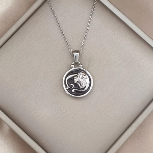 Detail of silver lion zodiac pendant with black enamel inlay in a jewelry box