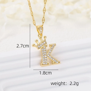 Gold crown letter K necklace pendant with white zircons on a white background