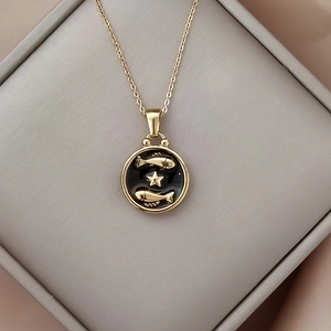 Close-up of golden zodiac necklace with black enamel Pisces pendant in a velvet box