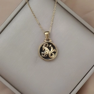 Detail of gold Capricorn necklace with black enamel pendant and star in a gift box