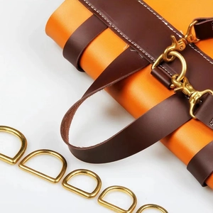 Détail de sac en cuir orange et marron avec anneau en D doré sur fond blanc pur