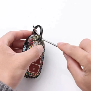 Close-up of a screwdriver installing the metal screw D-buckle on a leather key case