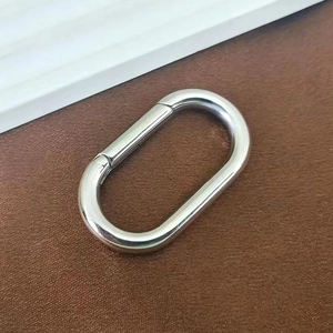 Macro shot of polished oval spring snap hook for handbags on dark leather background