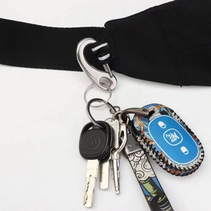 Detail of silver D-ring snap hook with keys and patterned charm on black strap