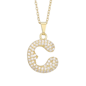 Macro detail of the golden necklace pendant featuring letter C with micro-pave zircons