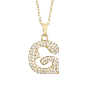 Macro shot of gold pendant letter G with sparkling white cubic zirconia stones