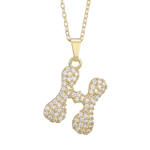 Detail of gold pendant necklace featuring letter H with sparkling pavé crystals