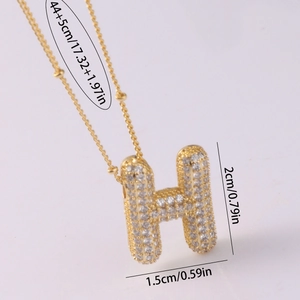 Dettaglio della collana con lettera H dorata e pavé di zirconi cubici scintillanti