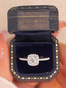 Macro shot of cushion-cut halo ring with pavé diamonds in a vintage blue velvet box