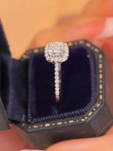 Macro shot of halo set round zircon ring inside a premium blue velvet hexagonal gift box