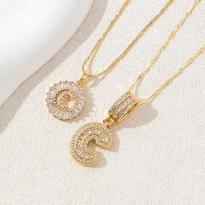 Detail of gold letter C pendants with micro-paved white zircons on fine box chains
