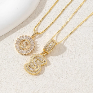 Detail of gold letter S pendants featuring sunburst design and iced out bubble style with cubic zirconia