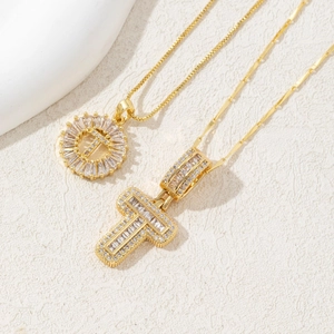 Detailed close-up of gold T-letter pendant and cross necklace with micro-pave zircons