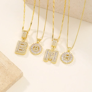 Collane placcate in oro con lettere in zirconi brillanti su un decoro in pietra arenaria