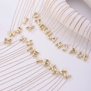 Gepolijste 18K vergulde bubbelletter hangers aan fijne kettingen op witte standaarden