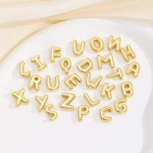 Detailaufnahme goldener 3D-Alphabet-Anhänger im Ballon-Stil mit hochglanzpolierter Oberfläche