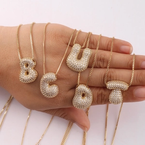 Detail of gold bubble letter pendants with sparkling zircon stones and box chain