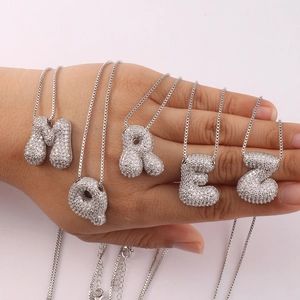 Close-up of silver-tone chunky letter pendants M Q R E Z with cubic zirconia stones